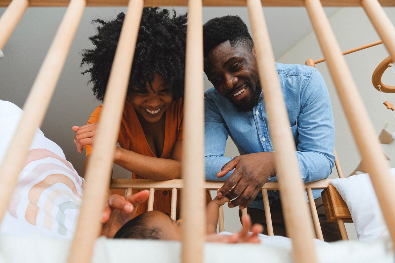 why-choose-us Joyful parents playing with their baby in a wooden crib.