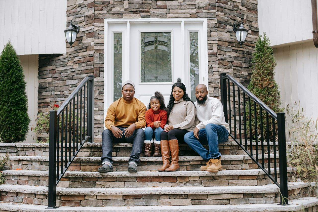 get-in-touch Young content African American parents with teenager and girl sitting on staircase near building while looking at camera