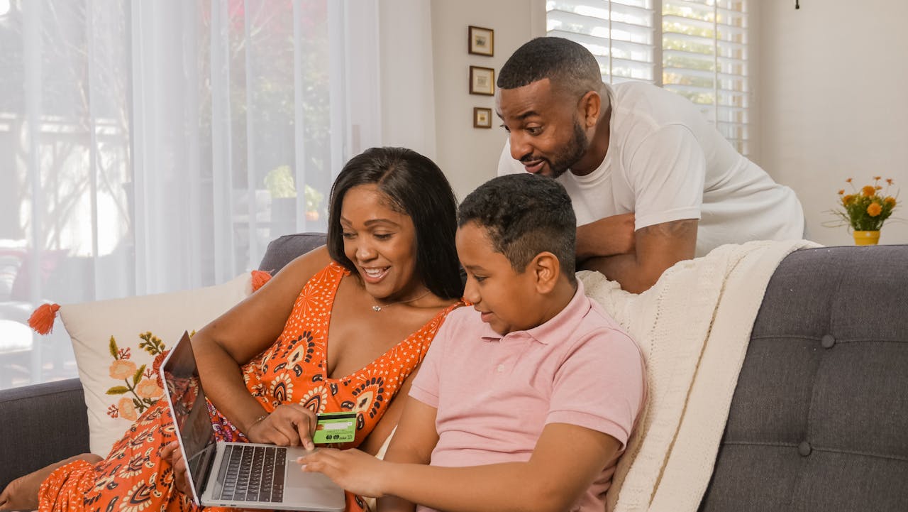 about-us A joyful family making an online purchase together on a laptop at their cozy home.